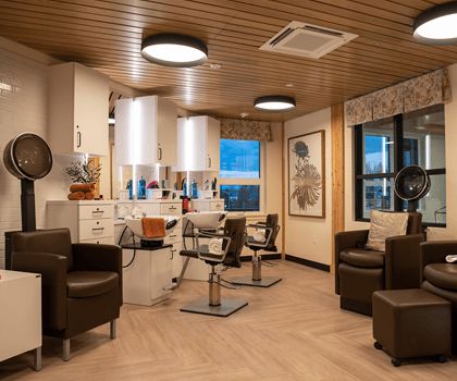 A modern hair salon with comfortable seating, large mirrors, and a warm wooden ceiling.