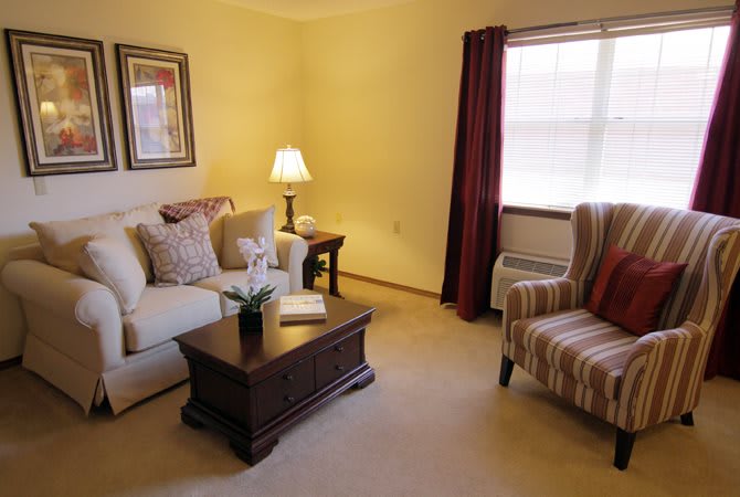 A cozy living room featuring a sofa and armchair, with a coffee table and lamp adding warmth to the space.