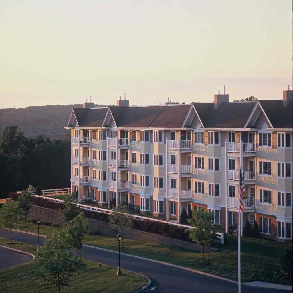 A residential apartment building at sunset surrounded by trees and a road.