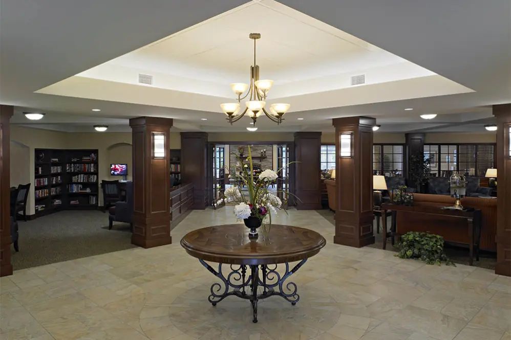 A spacious and elegant lobby with a central table, chandelier lighting, and tasteful decor.