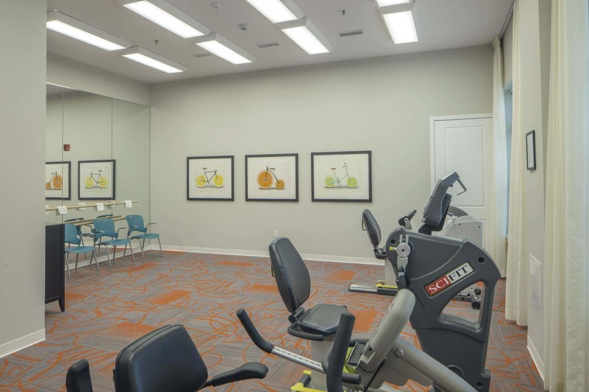 A small gym room with stationary bikes and framed artwork on the walls.