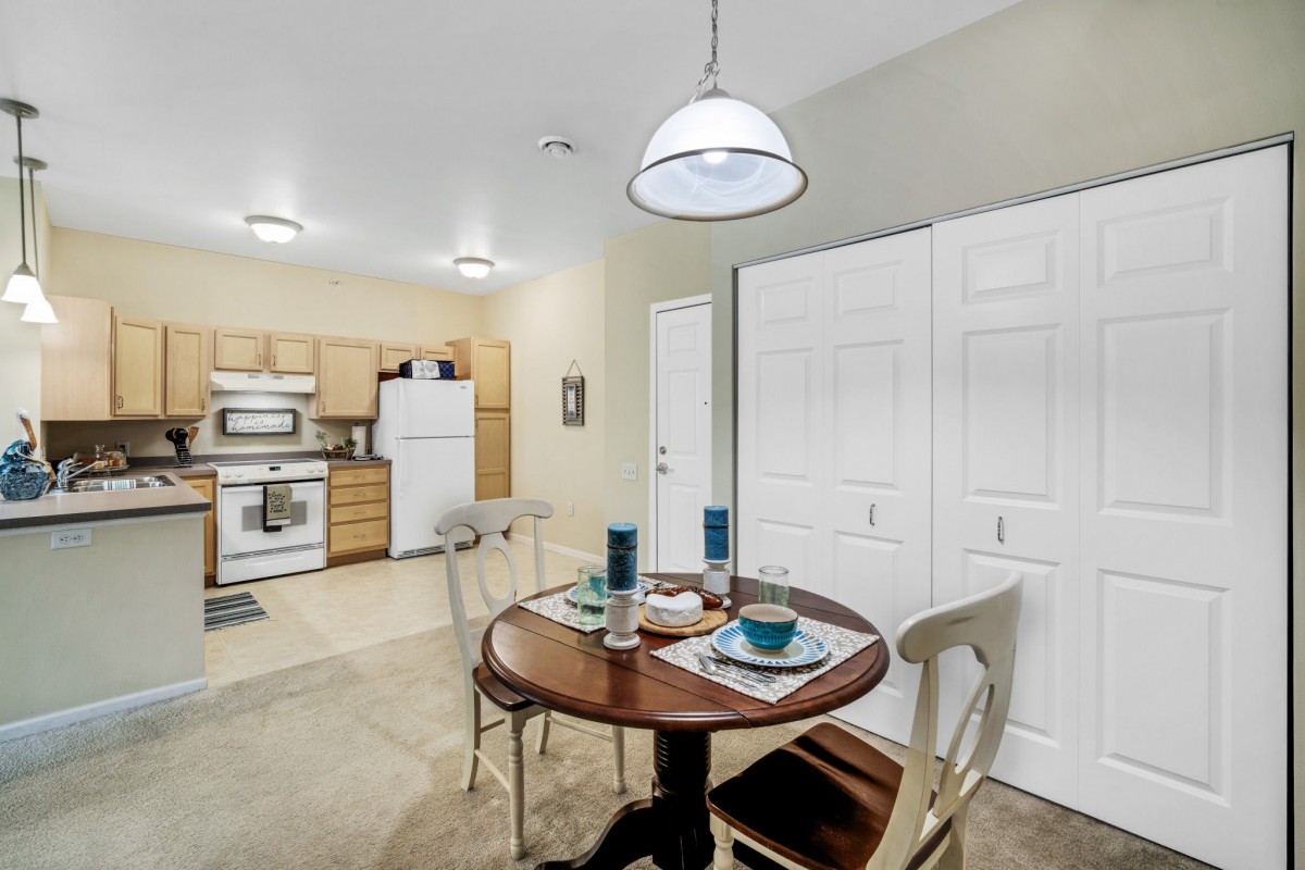 A cozy dining area with a round table set for two, adjacent to an open kitchen.