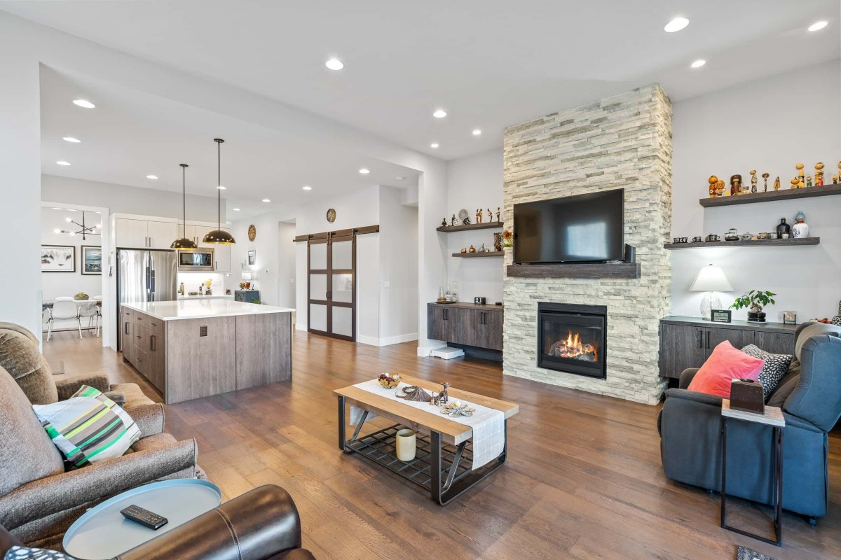 A modern open-concept living area featuring a cozy fireplace and adjoining kitchen.