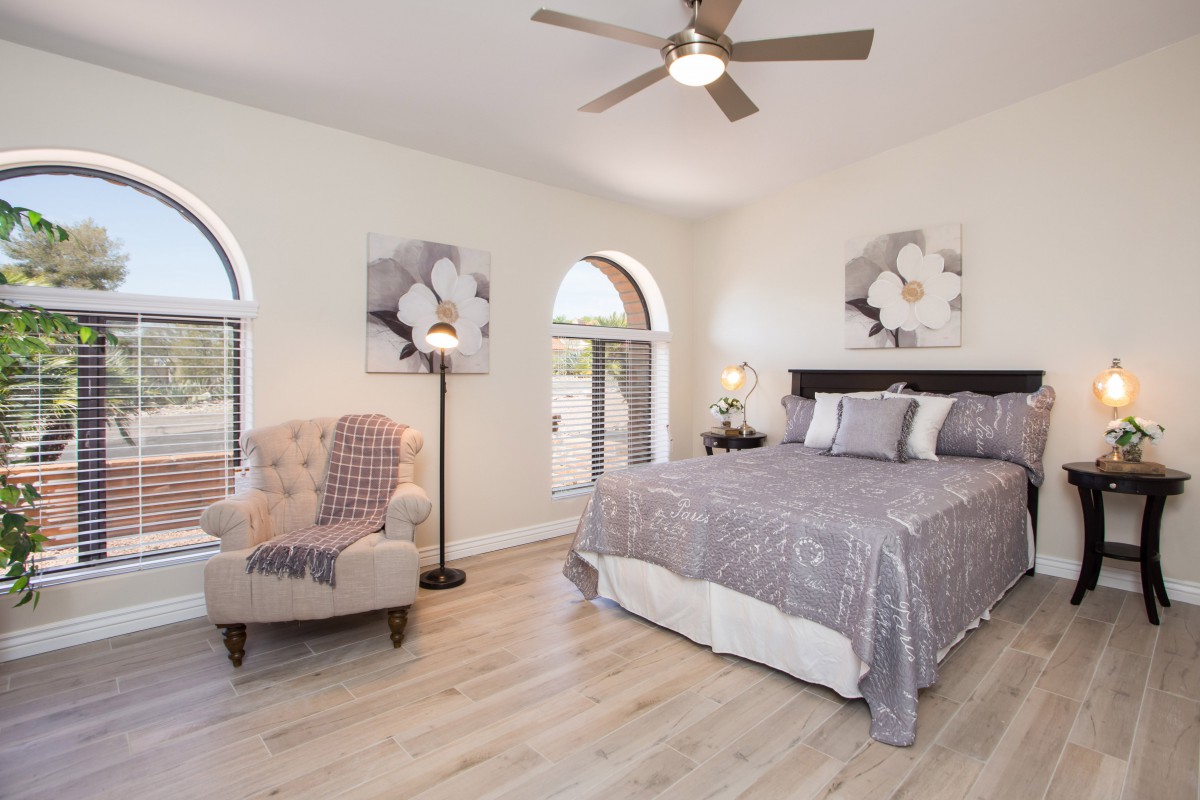 A modern bedroom with stylish decor, featuring a comfortable bed, an armchair, and decorative artwork.