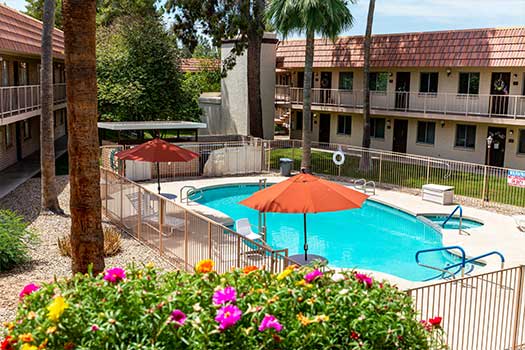 A serene outdoor hotel pool with blooming flowers and sun umbrellas.