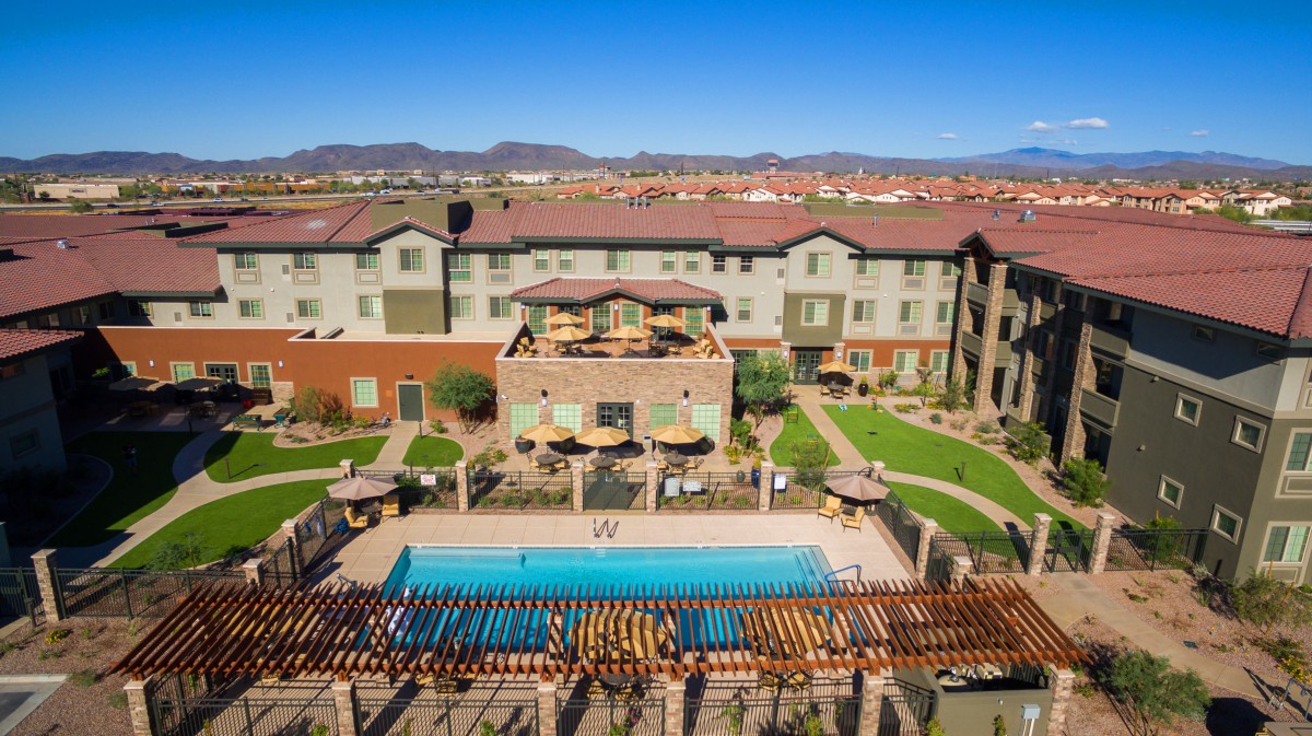 Aerial view of a hotel with a swimming pool set amidst landscaped gardens.