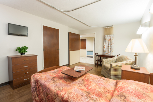 A cozy and inviting bedroom featuring a comfortable bed, seating area, and modern decor.