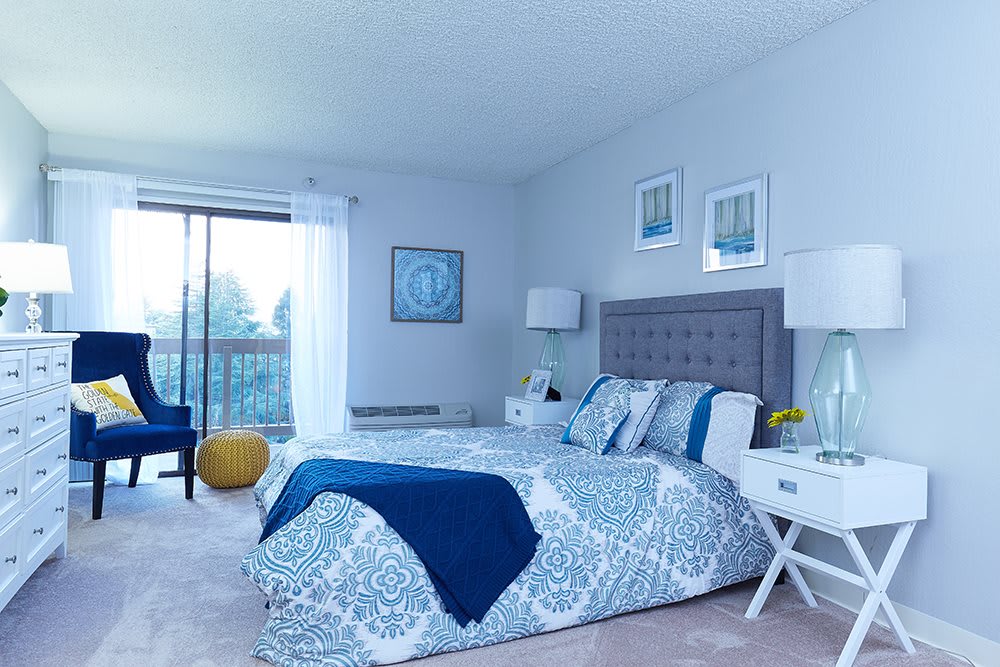 A modern bedroom with a blue and white color scheme, featuring a neatly made bed, stylish nightstands, and large windows.