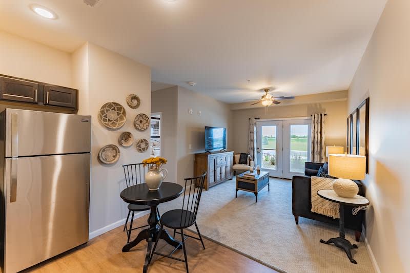 A cozy open-plan living and dining area with modern decor, featuring a small dining table, television, and tasteful wall art.