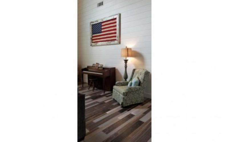 A cozy living room corner featuring a piano, armchair, and an American flag wall decoration.