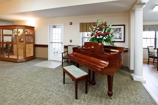 A room interior with a grand piano accompanied by a bench and floral arrangement.