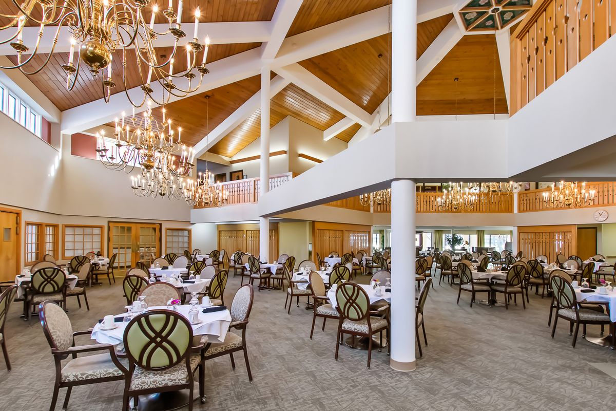 A spacious and elegantly designed restaurant dining area featuring chandeliers and neatly arranged tables and chairs.
