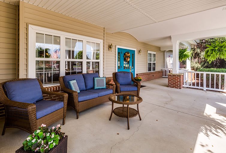 A cozy outdoor porch with wicker furniture and blue cushions, perfect for relaxation.
