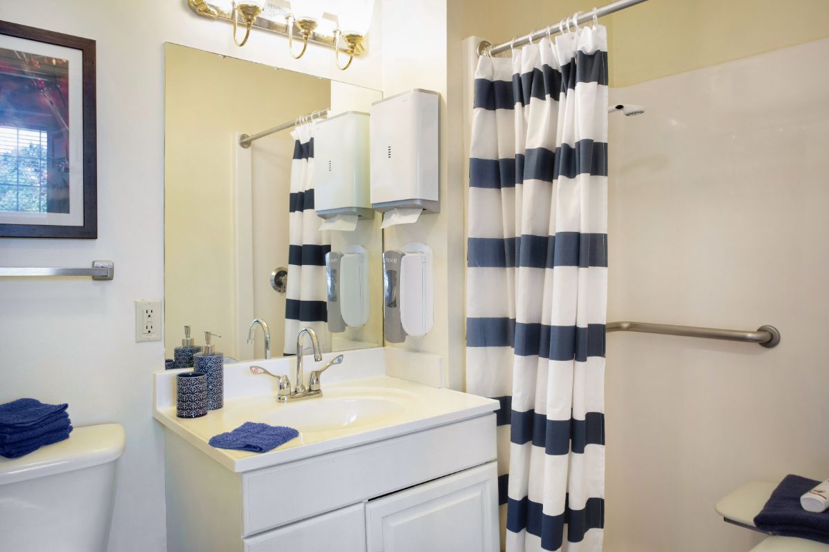 A tidy bathroom with a striped shower curtain and a neatly arranged sink area.