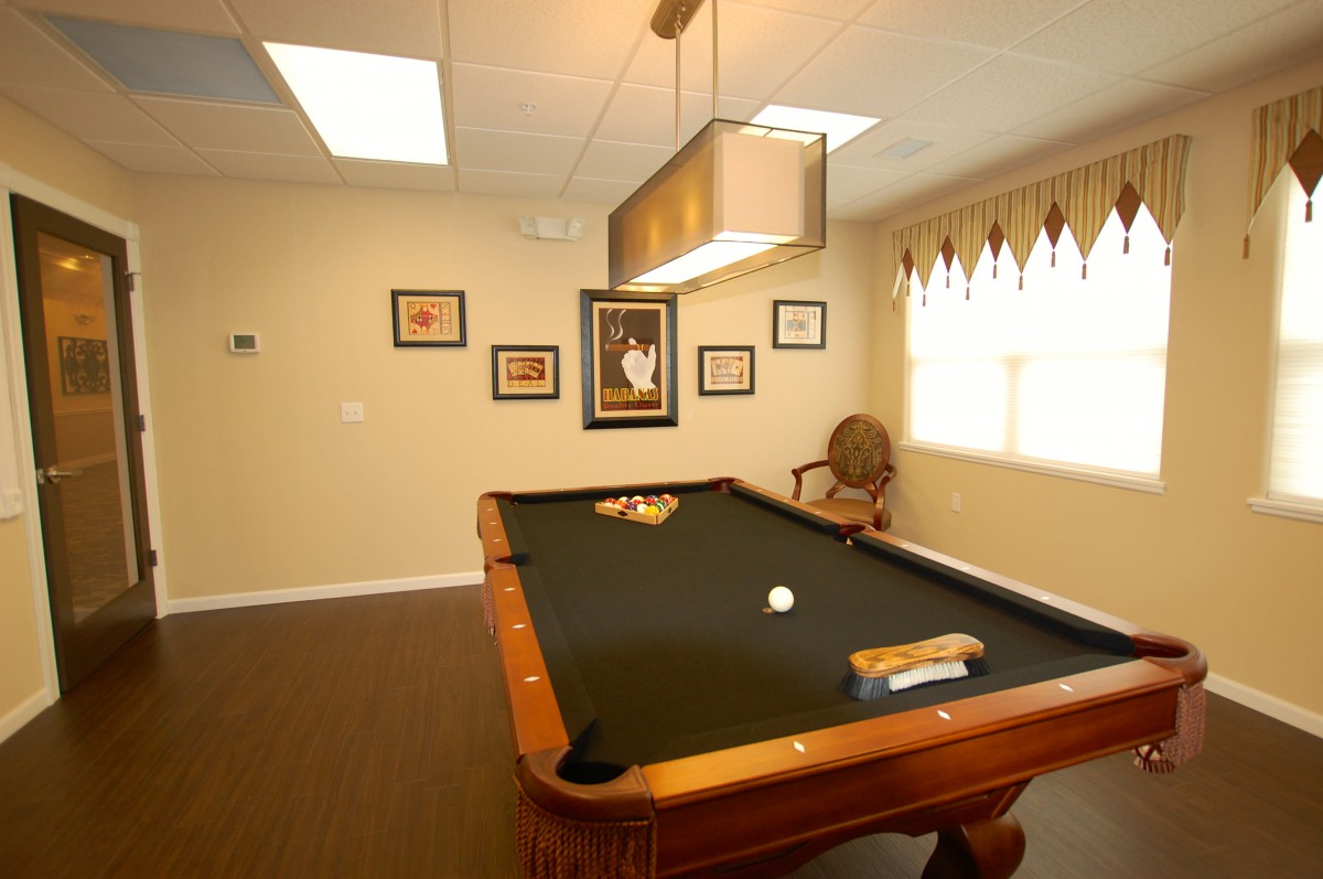 A cozy game room with a pool table and framed artwork on the walls.