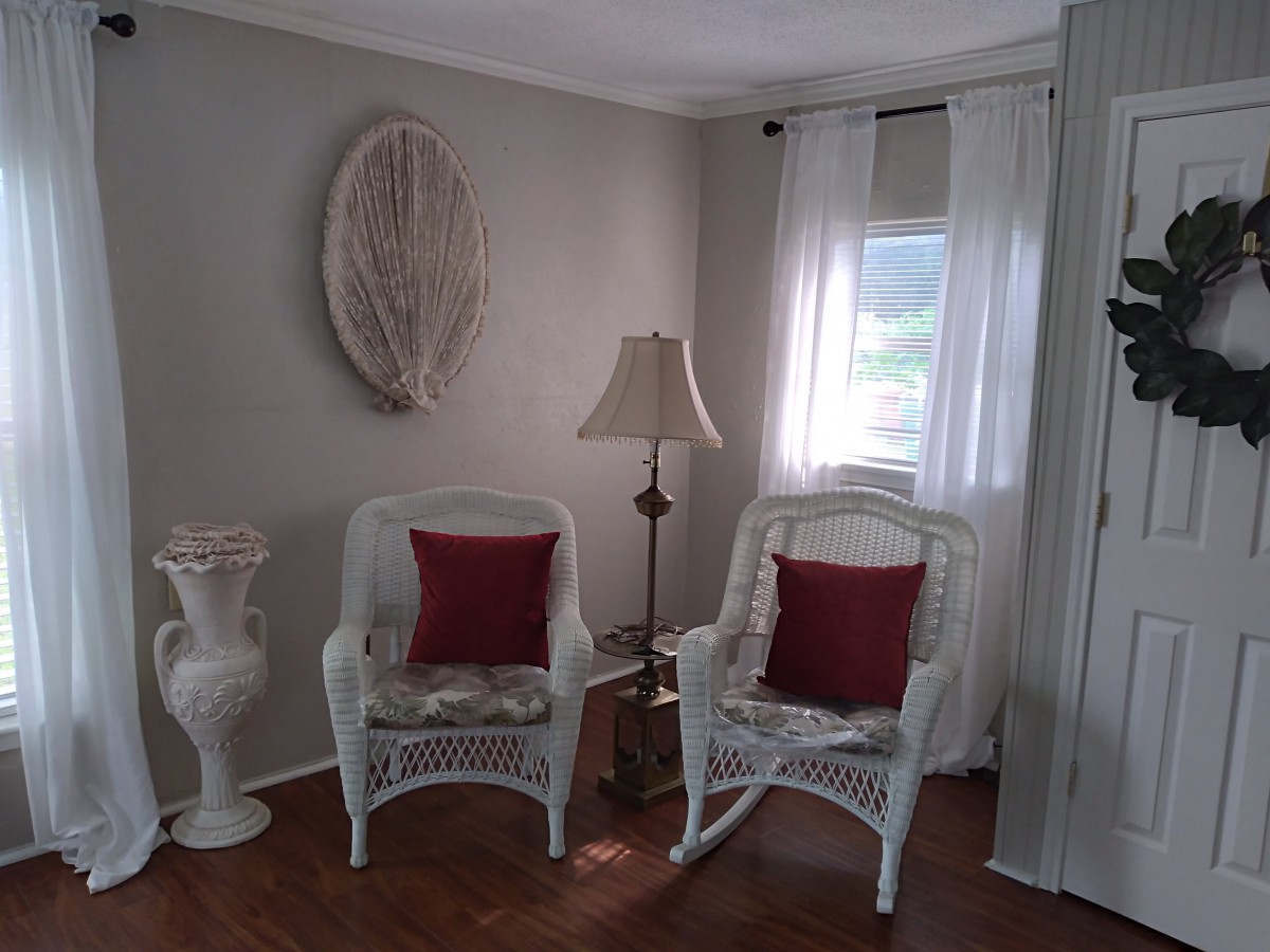 A cozy living room corner with wicker chairs and red cushions.
