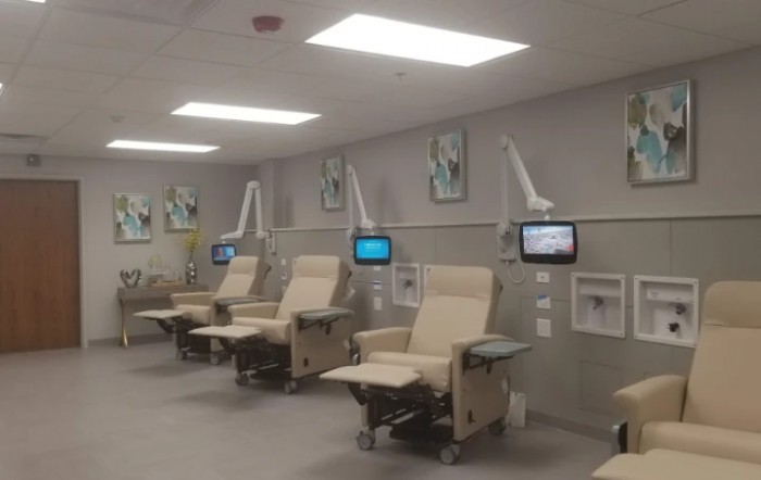A spacious hospital infusion room with treatment chairs and monitors.