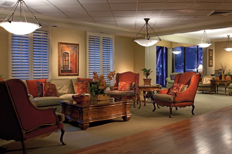 A traditionally styled living room featuring comfortable seating, elegant lighting, and decorative artwork.