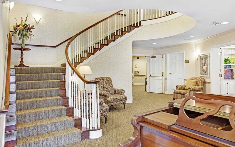 A lobby with a curved staircase and comfortable seating.