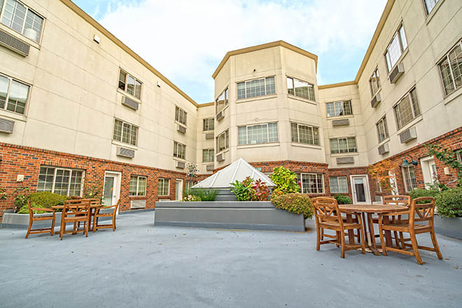 A serene courtyard with outdoor seating surrounded by a multi-story building.