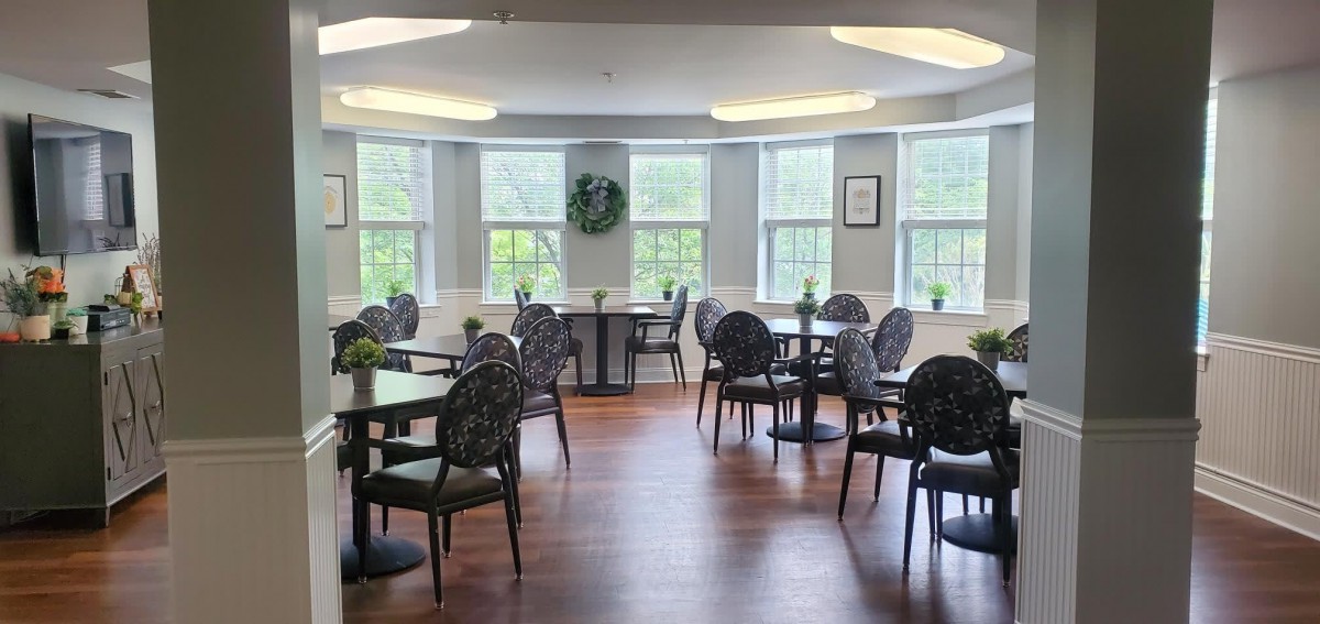 A well-lit dining area with several tables and chairs, featuring large windows that allow natural light to fill the space.
