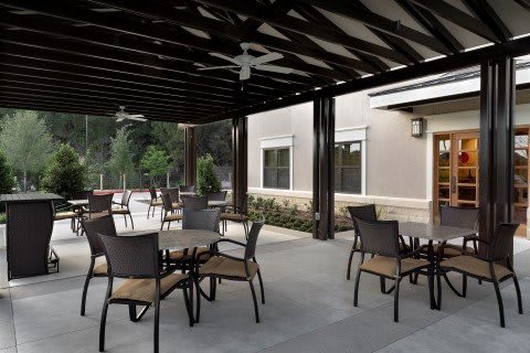 A cozy outdoor patio with a pergola featuring tables and chairs, perfect for relaxation or dining.