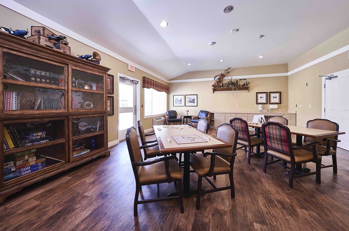 A cozy dining room with wooden floors, a large table surrounded by chairs, and decorative elements on the walls.