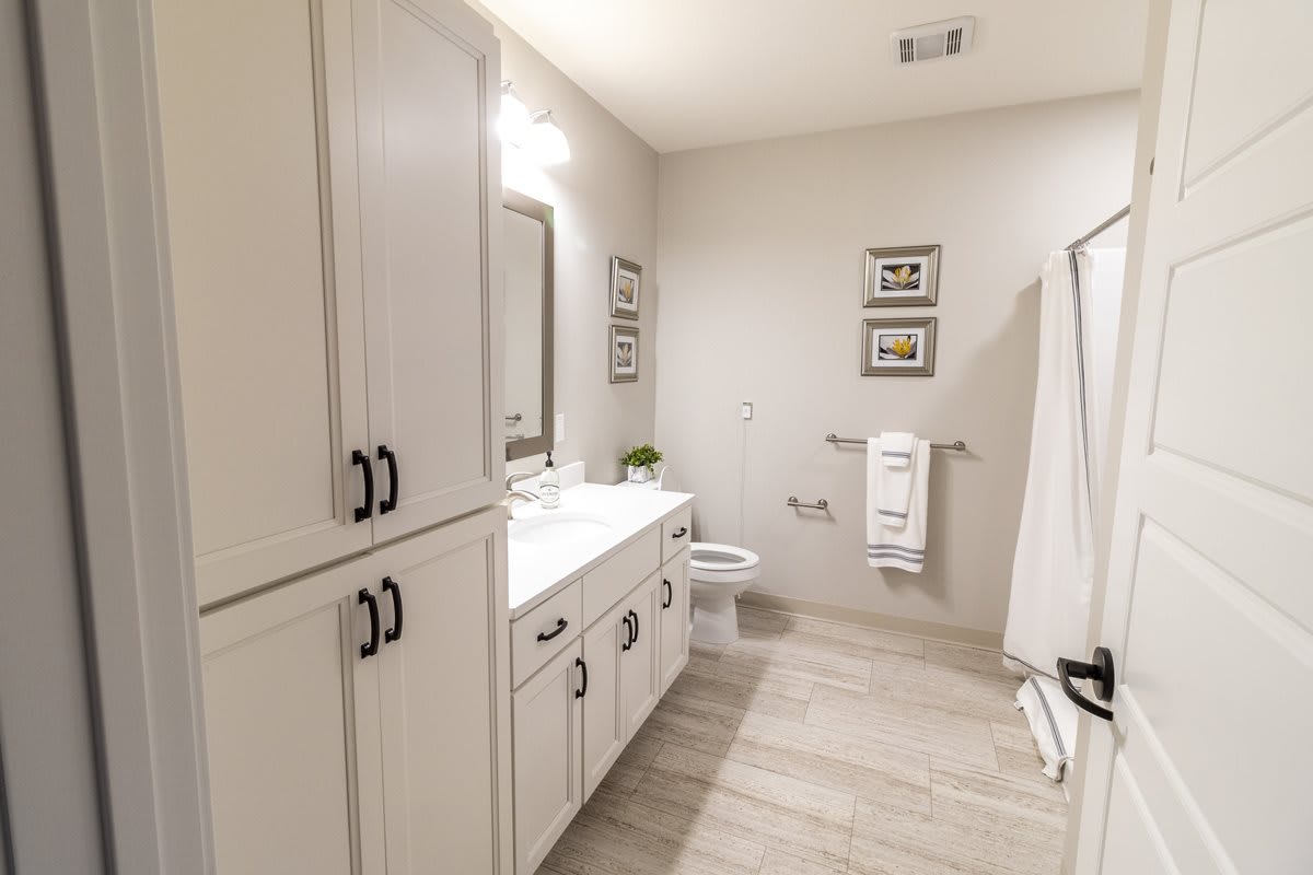 A modern bathroom featuring white cabinetry, a large mirror, and elegant decor.
