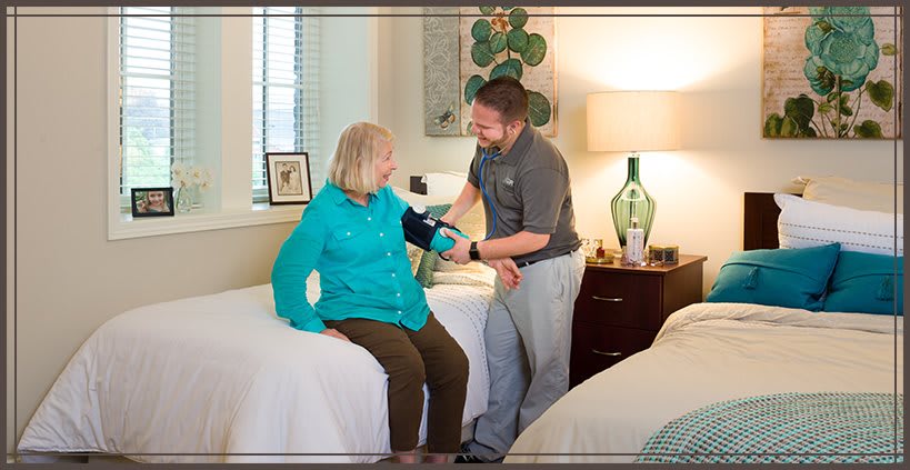 A healthcare professional takes the blood pressure of a patient in a hospital room.