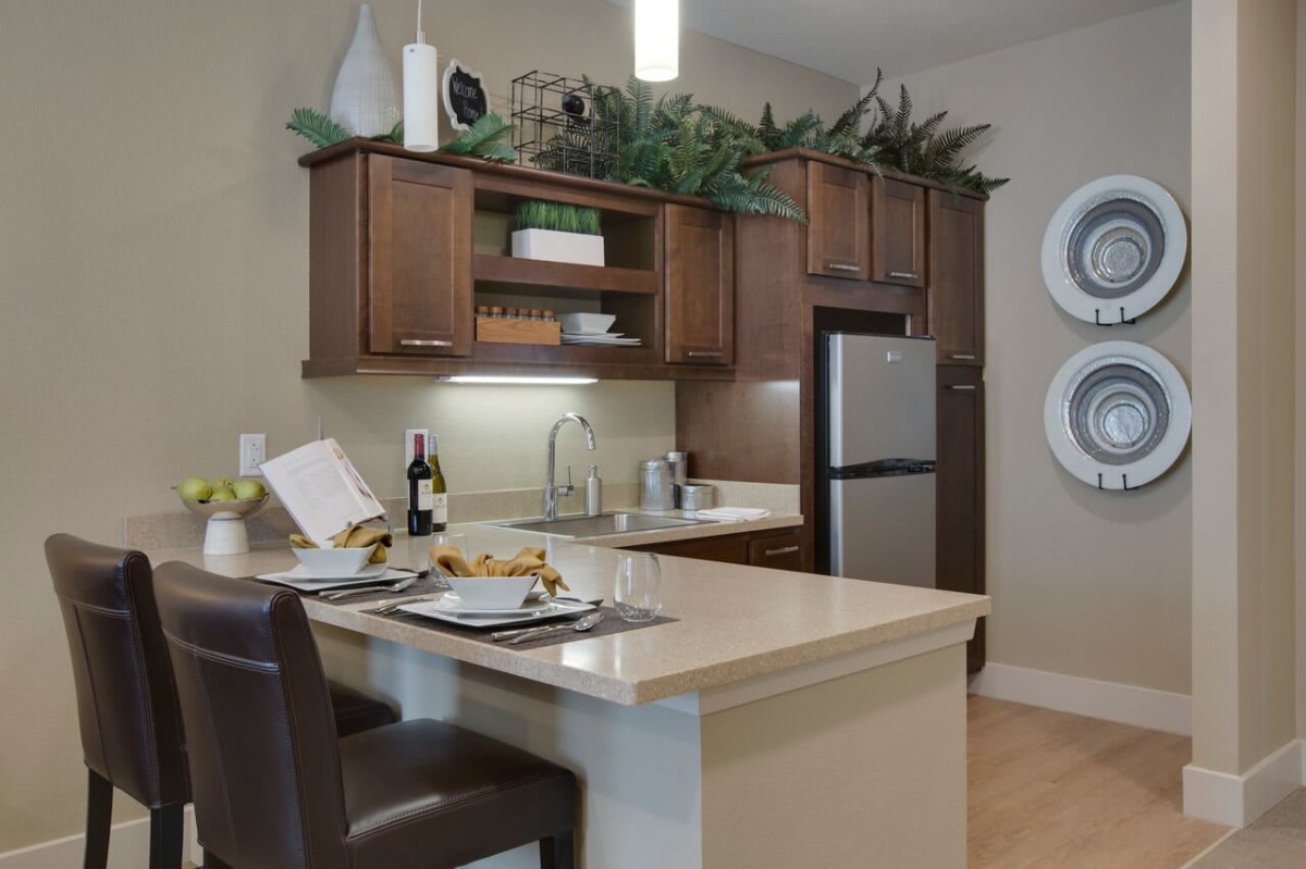 A modern kitchen with wooden cabinets, a kitchen island with seating, and stainless steel appliances.