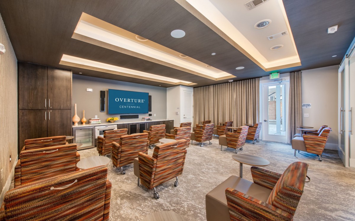 A modern conference room with theater-style seating and a large presentation screen.