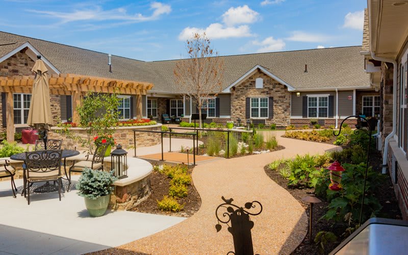 A beautifully landscaped courtyard with a path leading to a stone building under a clear blue sky.