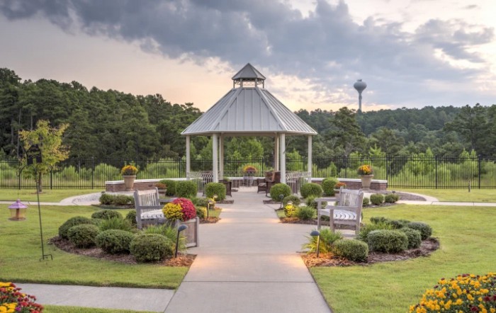 A scenic garden with a central gazebo surrounded by lush greenery and benches.