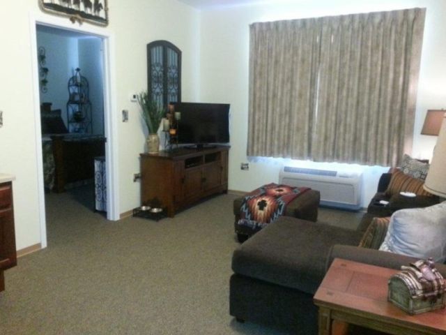 A cozy living room with a sofa, television, and curtains.
