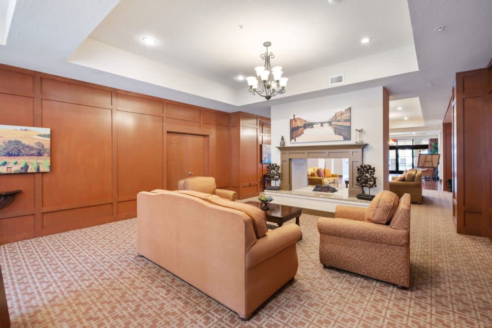 A cozy living room featuring a set of sofas, a fireplace, and a chandelier.