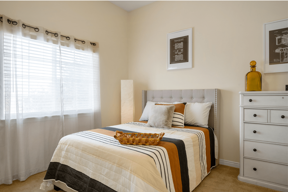 A cozy bedroom with a neatly made bed featuring striped bedding and decorative pillows.