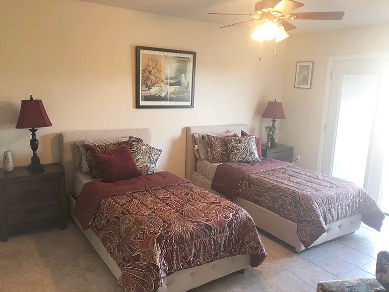 A cozy bedroom featuring two twin beds with decorative bedding and artwork on the wall.