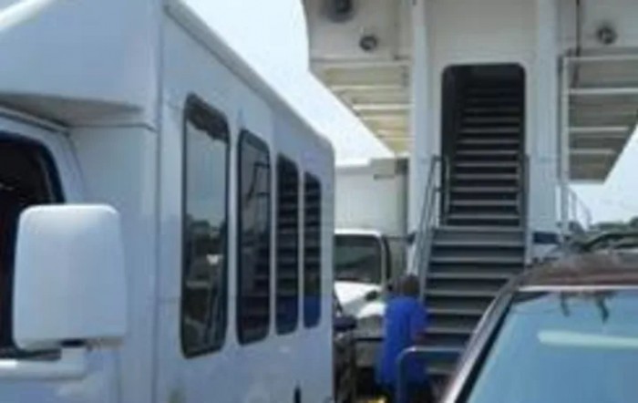 A bus parked next to stairs on a sunny day.