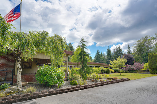 A charming residential home surrounded by lush greenery and trees under a cloudy sky.
