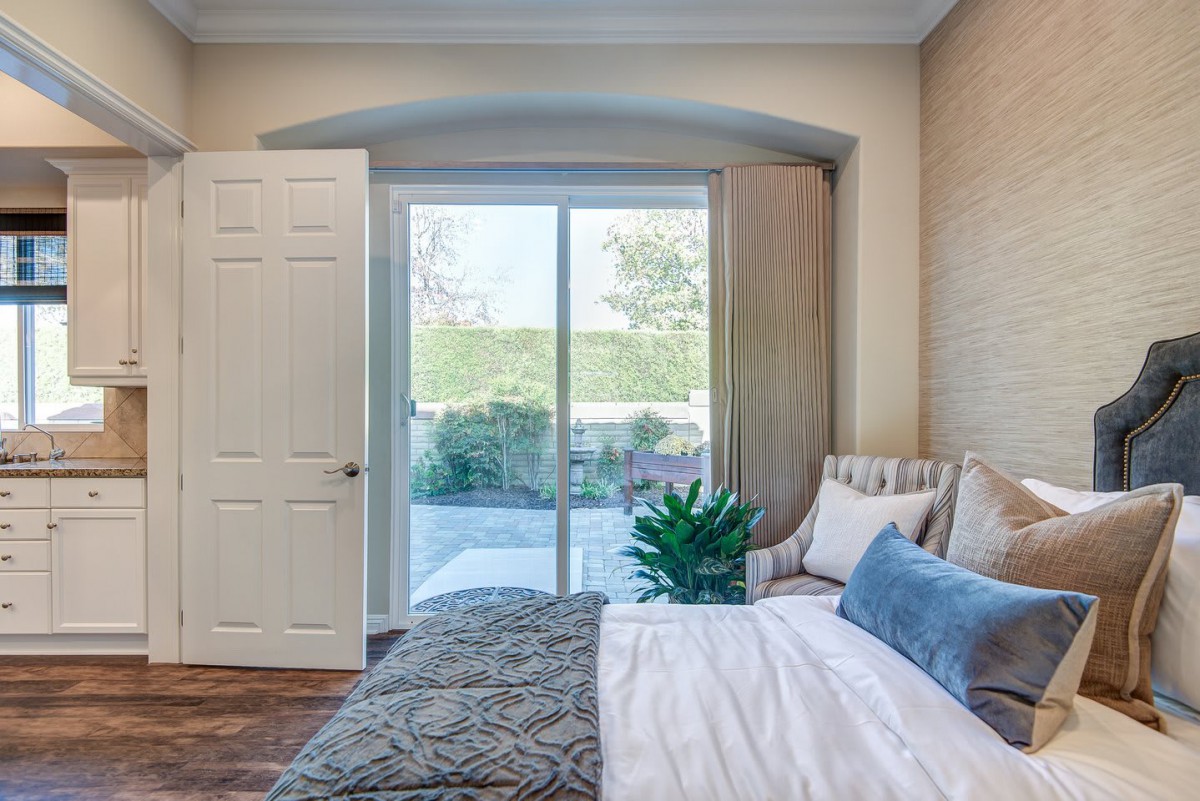 A cozy bedroom with a comfortable bed, large window letting in natural light, and minimalist decor.