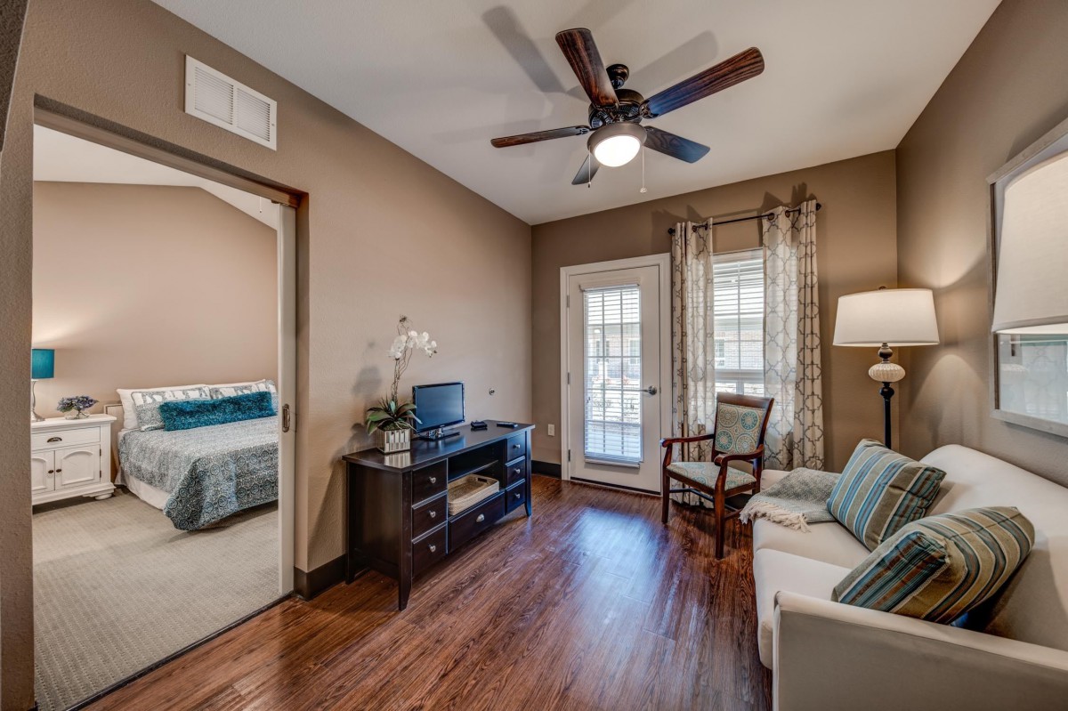 A cozy living room with a ceiling fan, wooden floors, and a comfortable seating area.