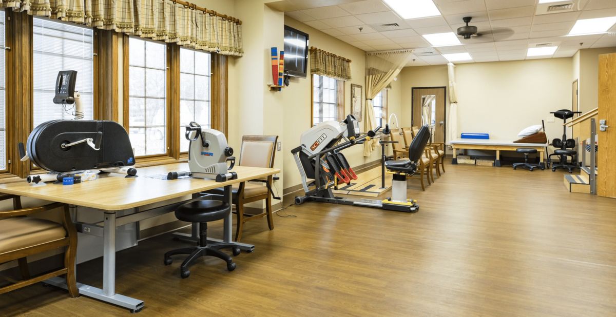 A rehabilitation room with therapy equipment and seating area.