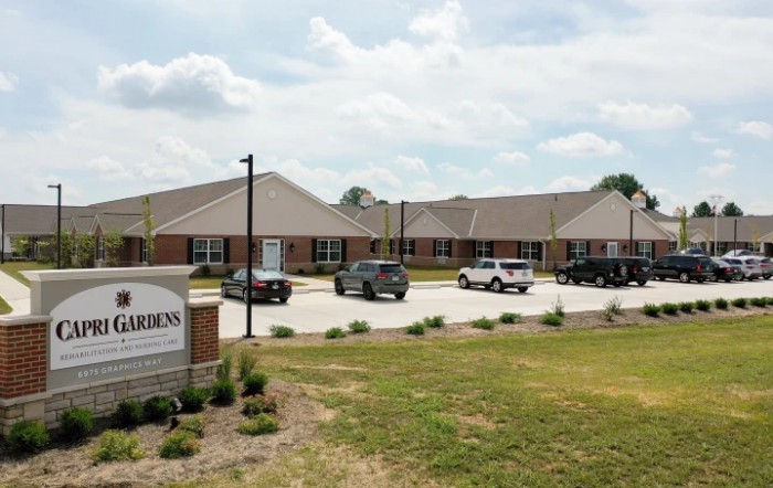 A view of a residential or commercial building with parked cars and a sign in the foreground.