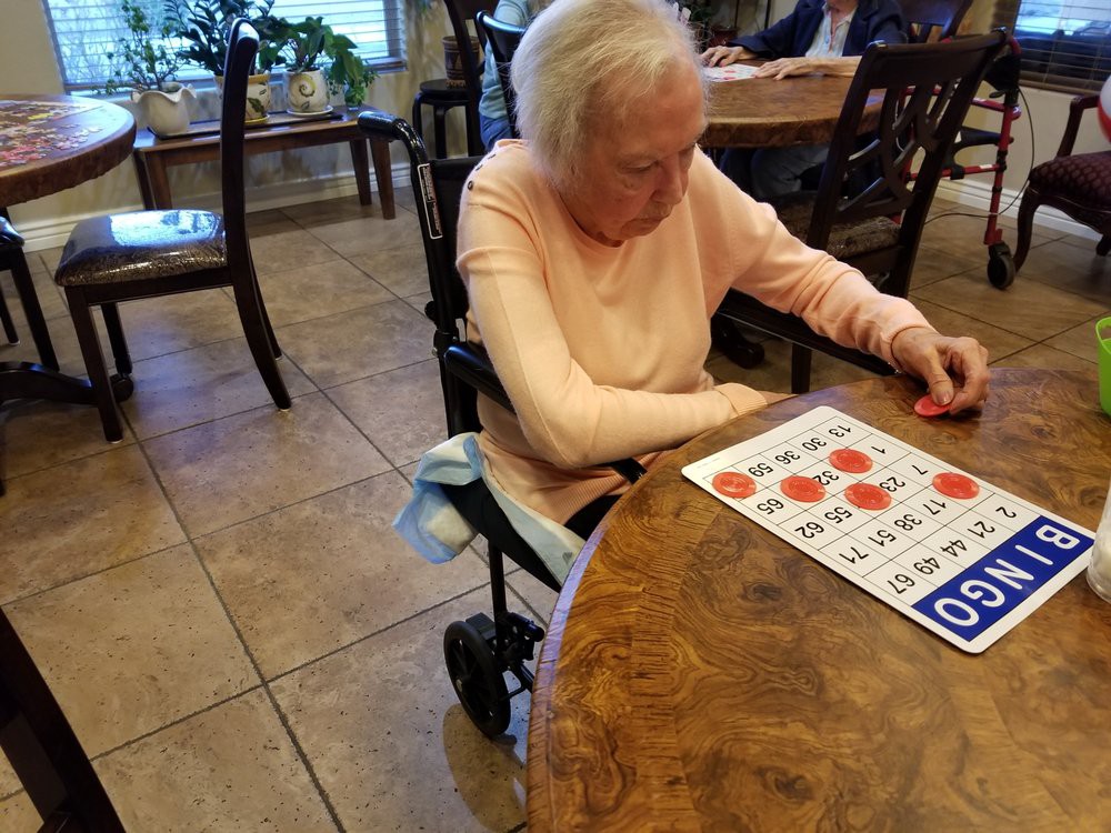 An elderly woman playing bingo at a table indoors.