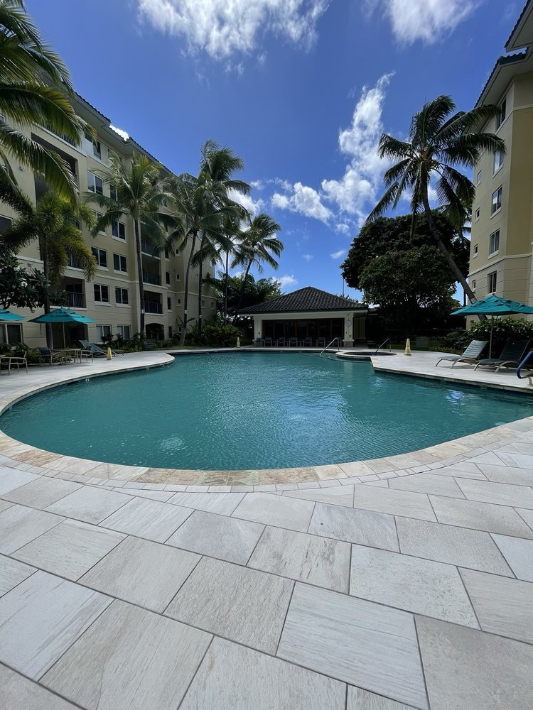 A tranquil outdoor swimming pool surrounded by palm trees at a tropical resort.