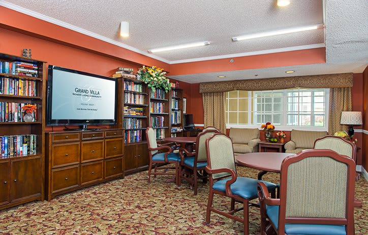A cozy living area with bookshelves and seating arrangements, featuring a television.