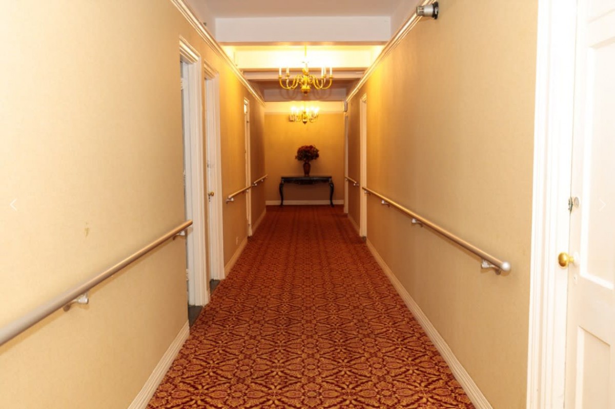 A warmly lit hallway with patterned carpet and a decorative table at the end.