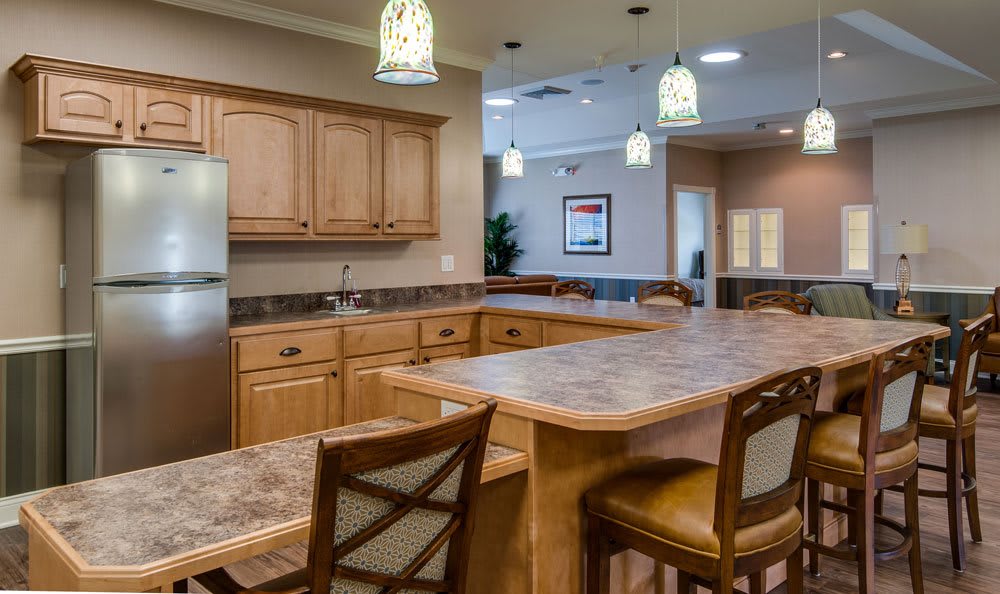 A modern kitchen interior featuring a large island countertop with bar stools and overhead lighting.