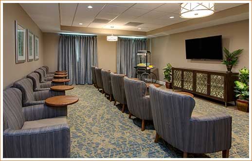A well-furnished conference room with rows of comfortable chairs and a large television.