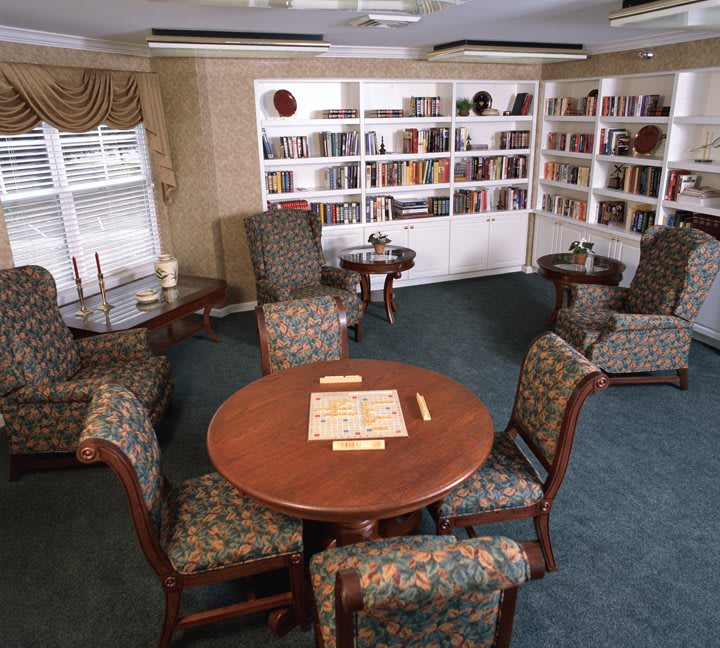 A cozy library corner with bookshelves and a table set for reading or board games.